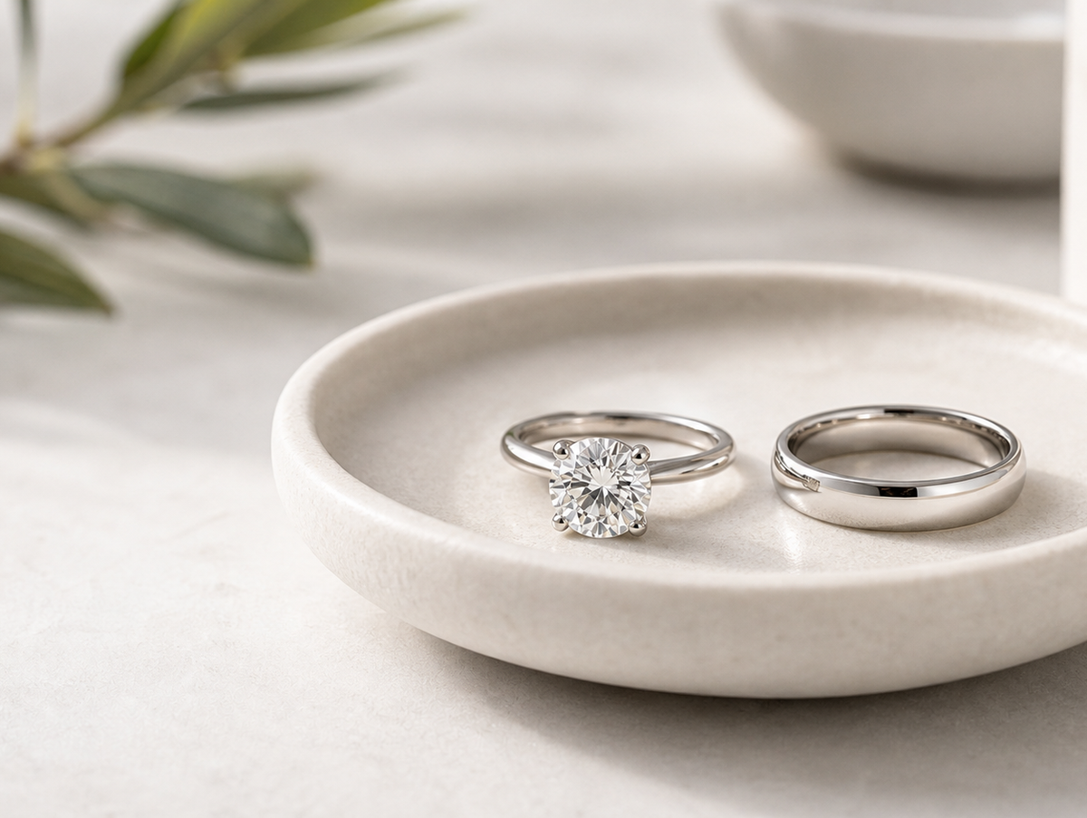 Diamond engagement ring and plain wedding band arranged together on a refined jewelry tray.