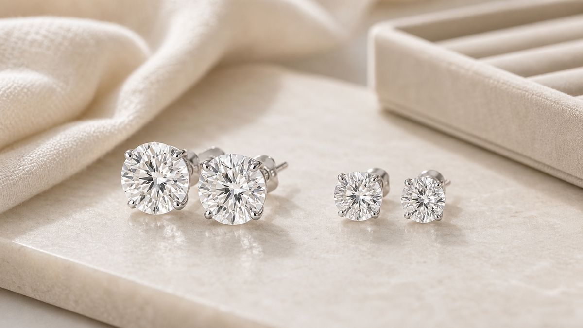 Diamond stud earrings in different sizes on a neutral jewelry surface