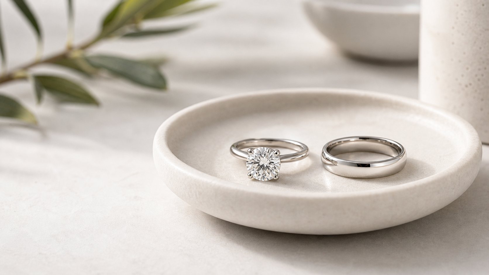 Diamond engagement ring and plain wedding band arranged together on a refined jewelry tray.