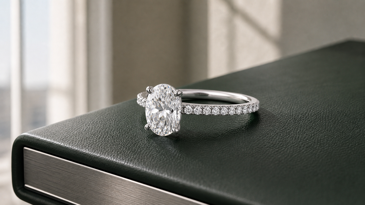 Oval diamond engagement ring with a slim pavé band on a dark green design portfolio.
