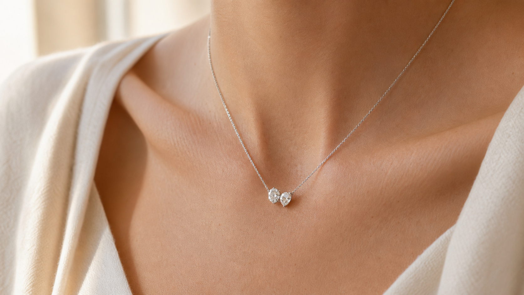 Toi et Moi necklace with two diamond-style stones worn at the collarbone in soft natural light.