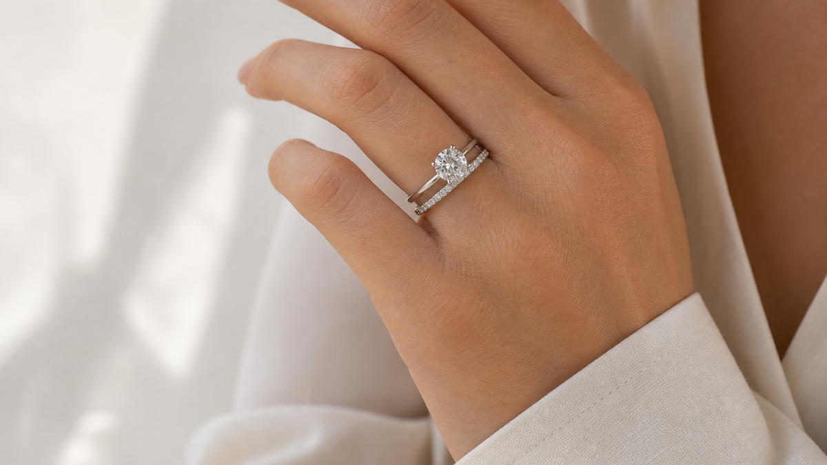 Solitaire engagement ring paired with a slim wedding band on the hand in soft daylight.