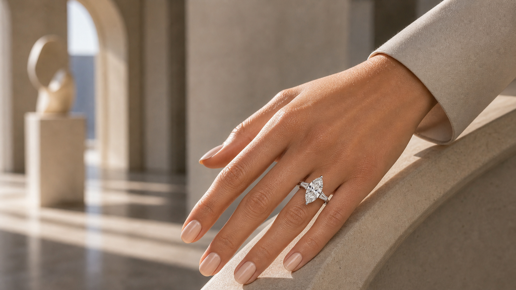Marquise diamond engagement ring worn on an elegant hand in warm architectural light.